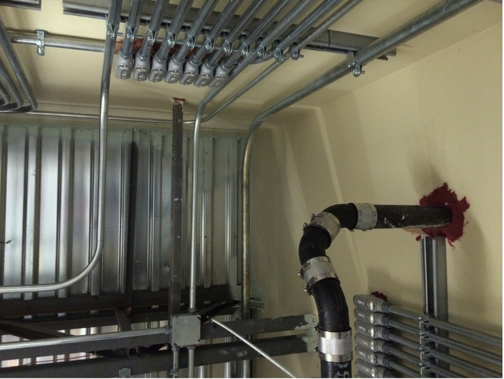 Red de Conduits Metálicos para Instalaciones Eléctricas Industriales. Se muestra red compleja de instalaciones eléctricas industriales con múltiples conduits metálicos montados en techos y paredes, incluyendo cajas de registro y soportes estructurales. Esta infraestructura es fundamental para el mantenimiento eléctrico continuo y la integración de sistemas de control y automatización.