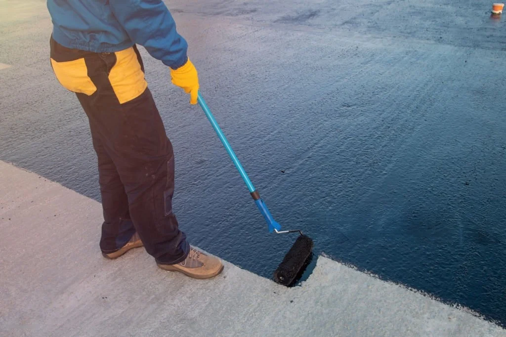 Técnico aplicando recubrimientos impermeables en losa de concreto para el servicio de impermeabilización industrial y protección de superficies